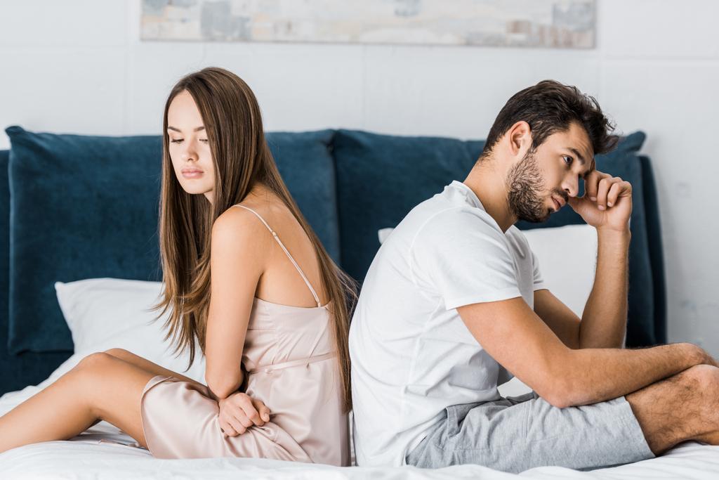 молодая депрессивная пара в пижаме, сидящая на кровати
 - Фото, изображение