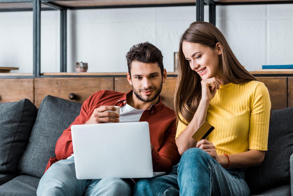 веселая пара делает покупки в Интернете и улыбается на диване
  - Фото, изображение