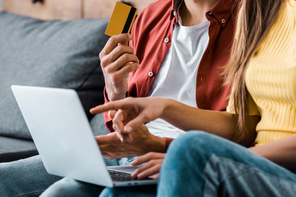 обрізаний вид чоловіка, який тримає кредитну картку і здійснює онлайн-покупки біля дівчини
 - Фото, зображення
