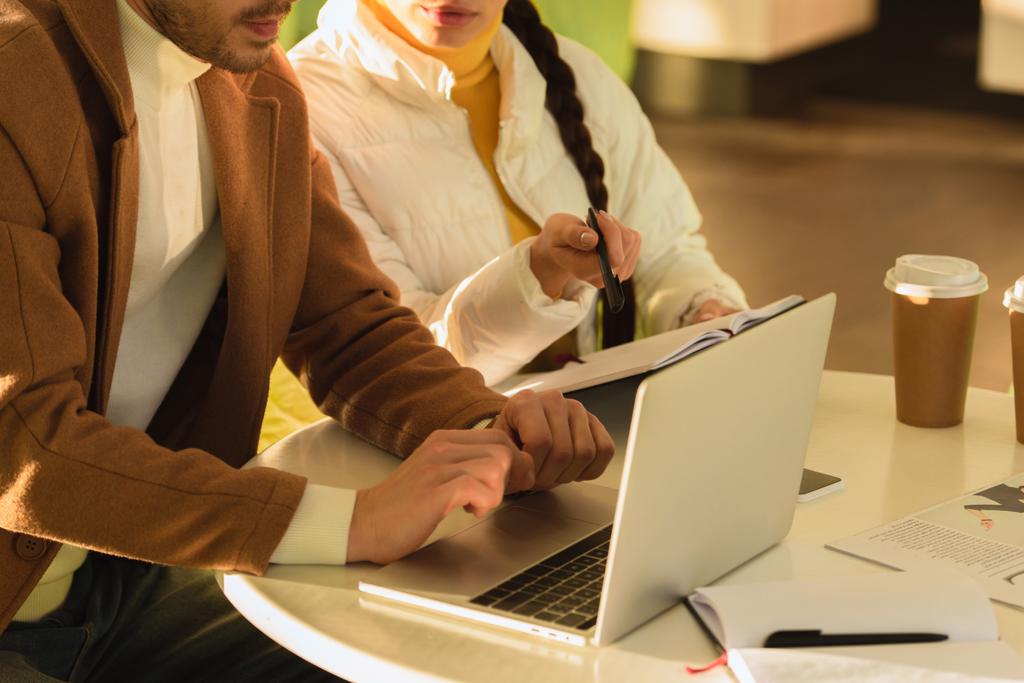 bijgesneden beeld van de man en meisje aan tafel zitten met laptop in café - Foto, afbeelding