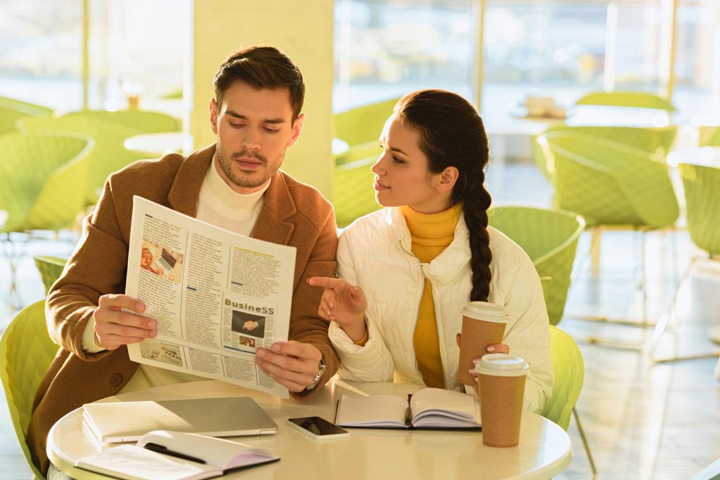 όμορφος άνδρας και ελκυστικό κορίτσι ανάγνωση επιχειρηματική εφημερίδα στο καφενείο - Φωτογραφία, εικόνα