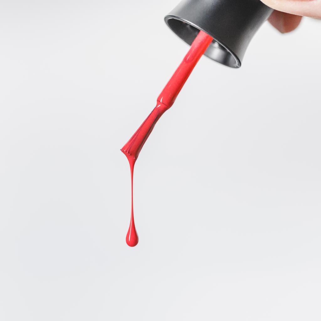 частичный вид женщины, держащей кисть с капающим красным лаком для ногтей изолирован на сером
 - Фото, изображение