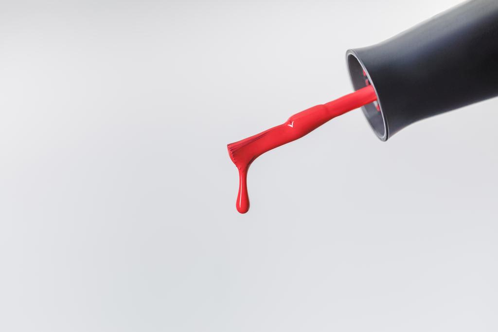 vista de perto da escova de esmalte com verniz vermelho gota isolada em cinza
 - Foto, Imagem