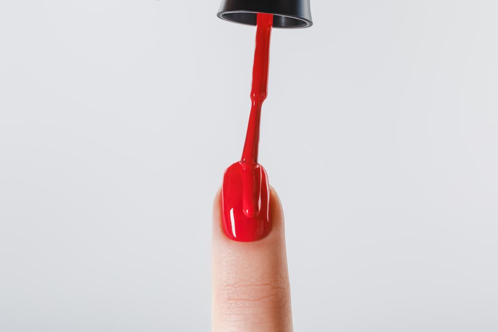 περικοπεί προβολή της γυναίκας εφαρμογή κόκκινο βερνίκι νυχιών στο νύχι που απομονώνονται σε γκρι - Φωτογραφία, εικόνα