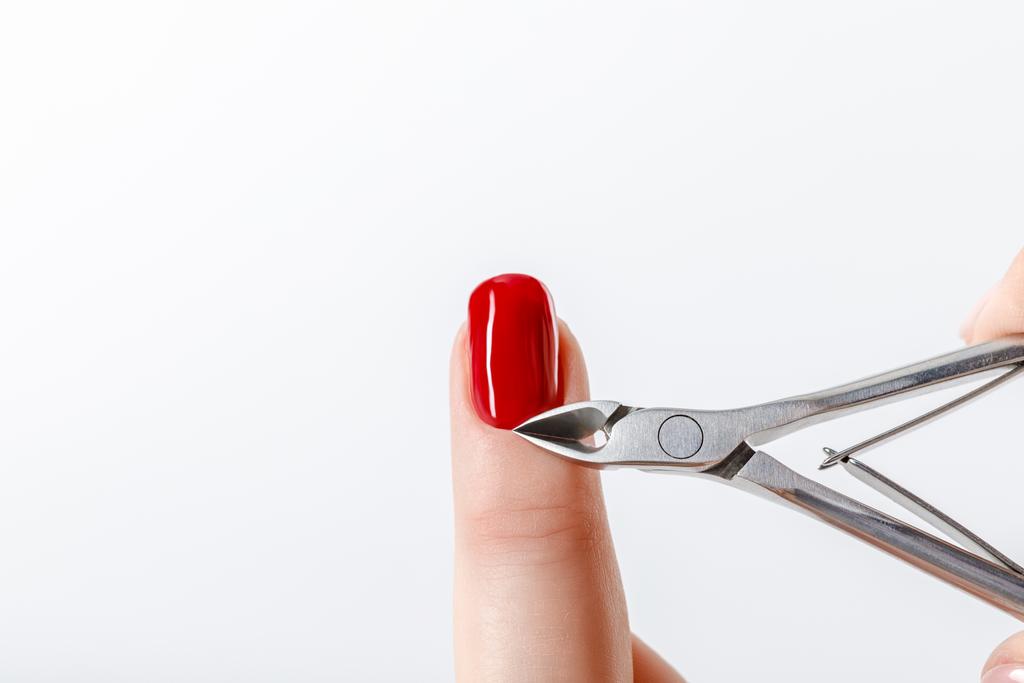 manucure à l'aide d'une pince à cuticule sur ongle avec vernis à ongles rouge isolé sur blanc
 - Photo, image