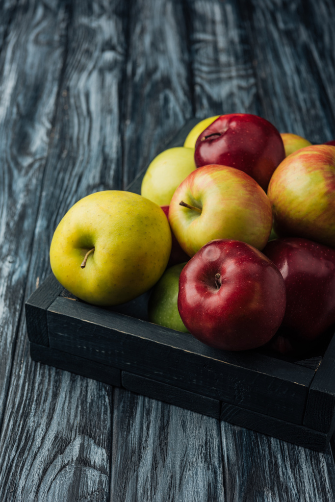 Caja de madera con manzanas maduras multicolores sobre mesa gris
  - Foto, imagen
