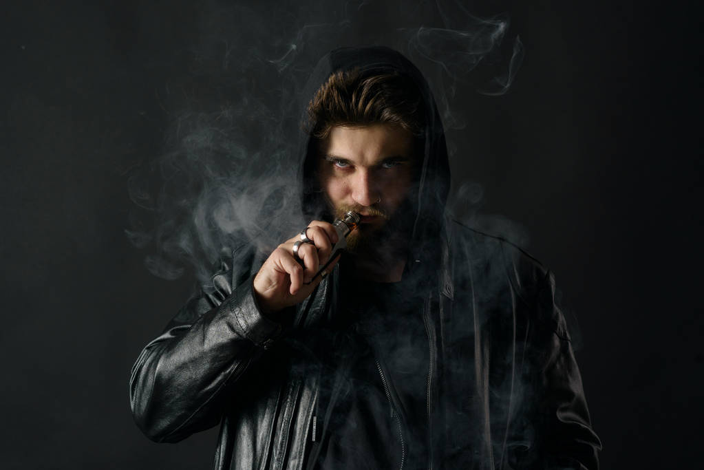 Adam vaping mod Buhar siyah stüdyo arka plan adlı parçasıyla birlikte kullanılmalıdır. Sakallı adam e-sigara tütün çıkmak için. Buharı ve alternatif nikotin ücretsiz Sigara kavramı - Fotoğraf, Görsel