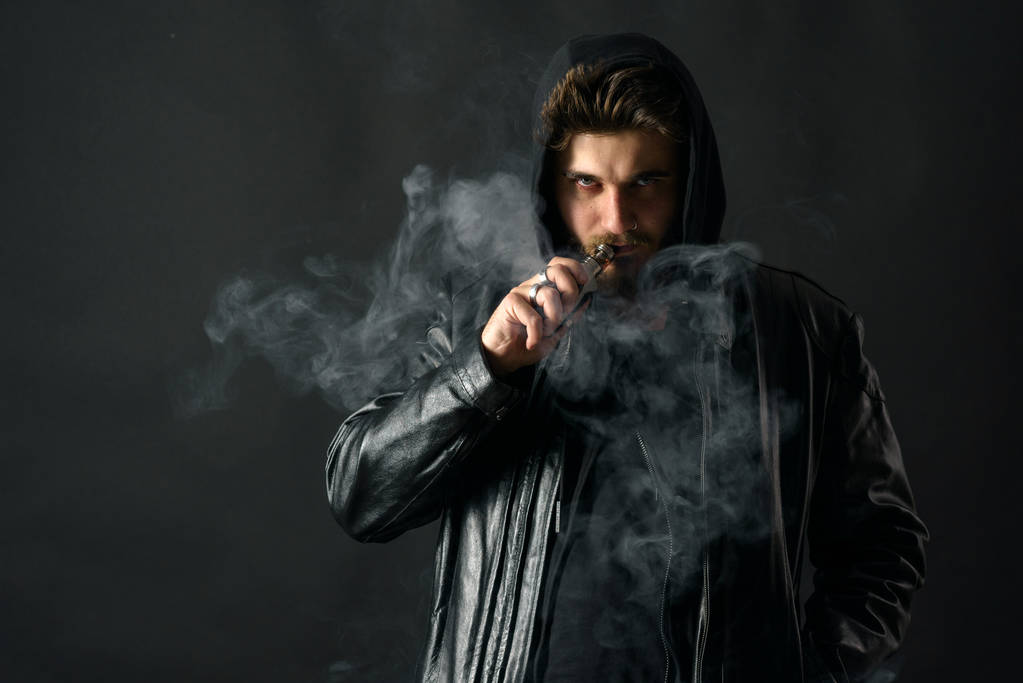 Adam vaping mod Buhar siyah stüdyo arka plan adlı parçasıyla birlikte kullanılmalıdır. Sakallı adam e-sigara tütün çıkmak için. Buharı ve alternatif nikotin ücretsiz Sigara kavramı - Fotoğraf, Görsel
