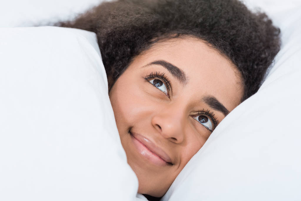 vista de cerca de la joven afroamericana acostada en la cama
  - Foto, imagen