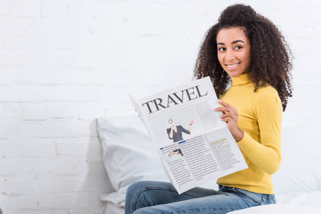 chica afroamericana rizada leyendo periódico de viaje en casa
 - Foto, Imagen