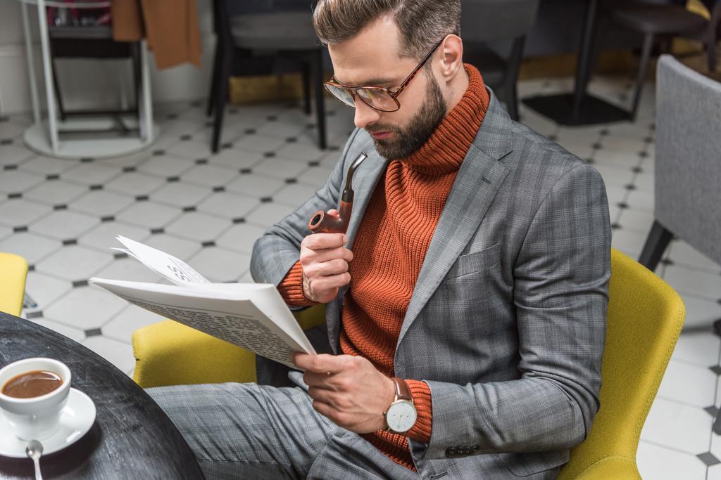 hombre elegante en ropa formal sentado en la mesa, leyendo el periódico y fumar pipa en el restaurante
 - Foto, imagen