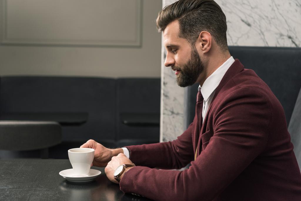 guapo hombre de negocios en ropa formal sentado en la mesa con una taza de café en el restaurante
 - Foto, Imagen