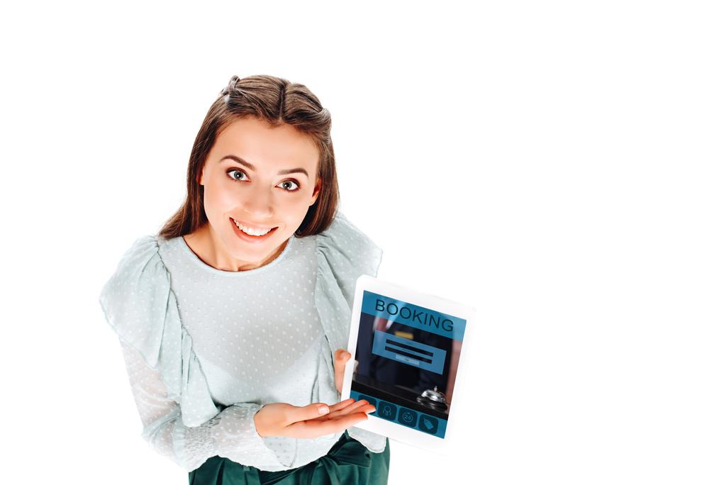 Hochwinkelaufnahme einer lächelnden jungen Frau mit Tablet mit Buchungsaufschrift isoliert auf Weiß - Foto, Bild