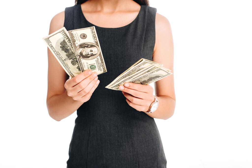 Teilansicht einer Frau im schwarzen Kleid, die Dollarnoten isoliert auf Weiß hält - Foto, Bild