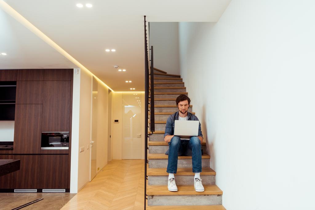handsome man sitting on stairs and using laptop - Photo, Image