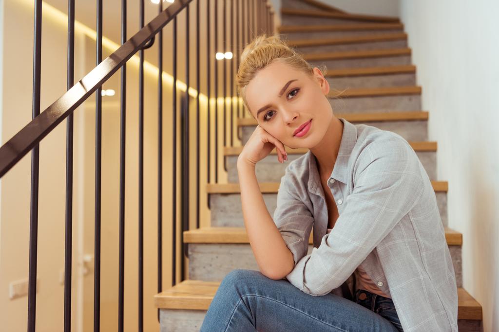 beautiful girl sitting on stairs and looking at camera - Photo, Image