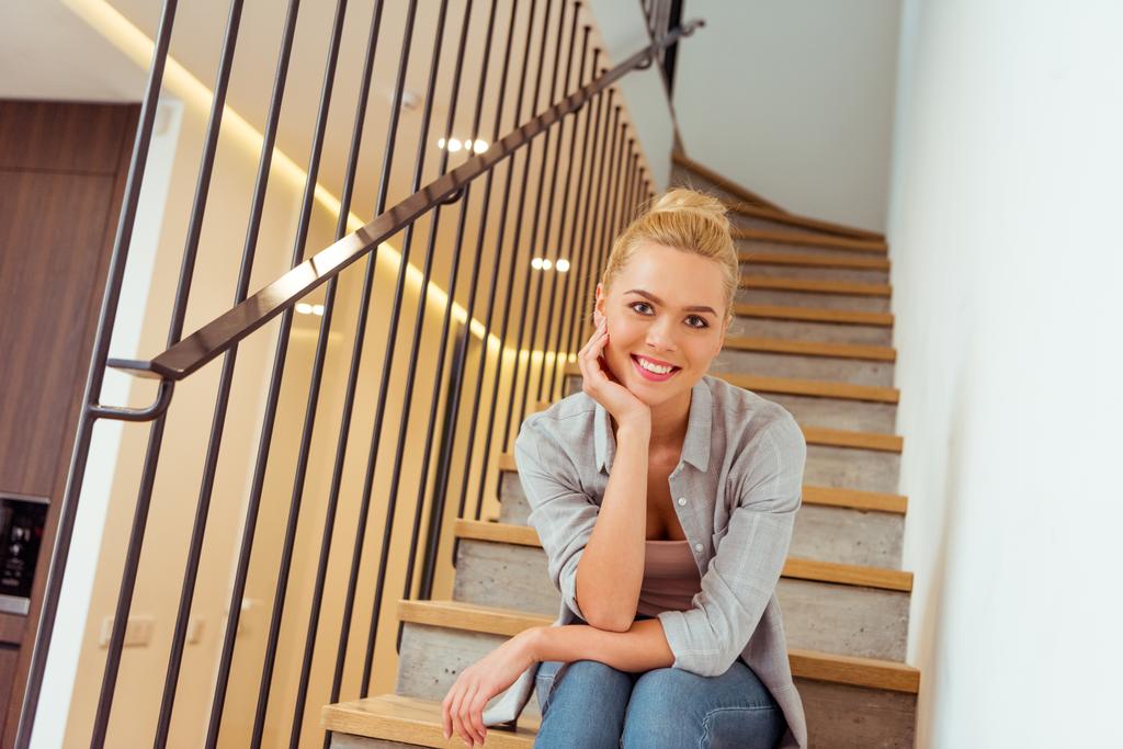 menina atraente sentado nas escadas, sorrindo e olhando para a câmera
 - Foto, Imagem