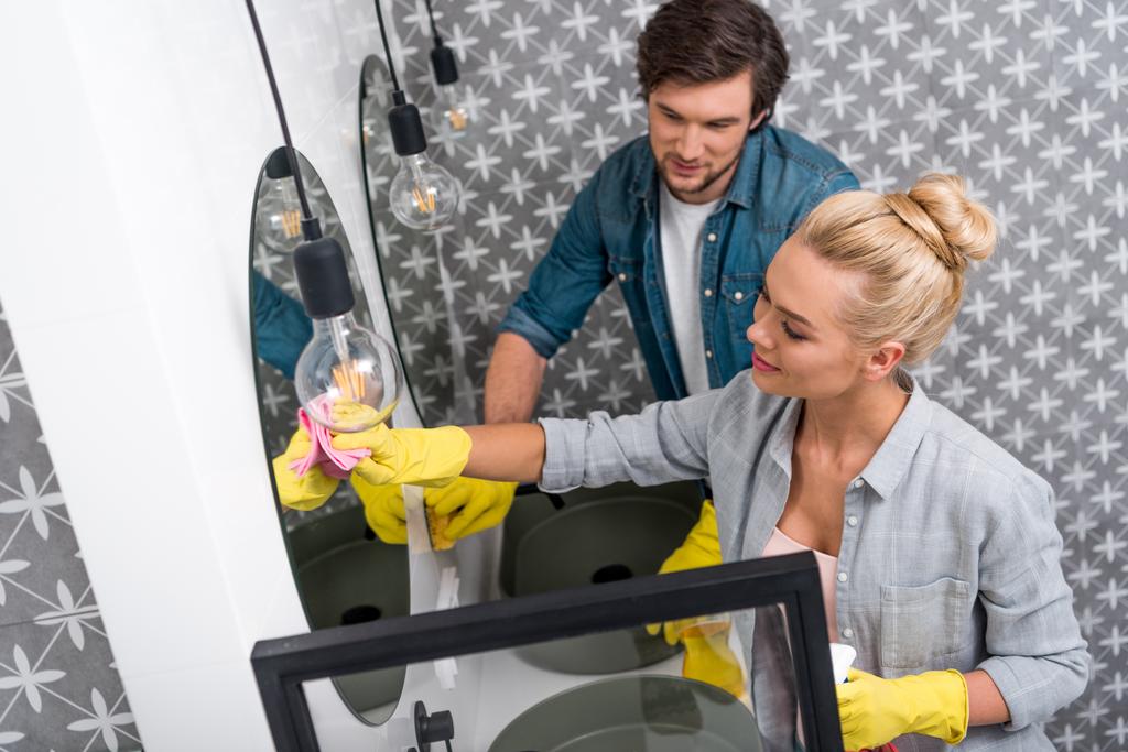 attrayant fille et bel homme en gants en caoutchouc miroir de nettoyage dans la salle de bain
 - Photo, image