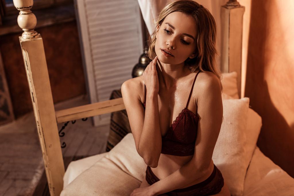 upea blondi nainen malli punainen pitsi alusvaatteita poseeraa sängyllä
 - Valokuva, kuva