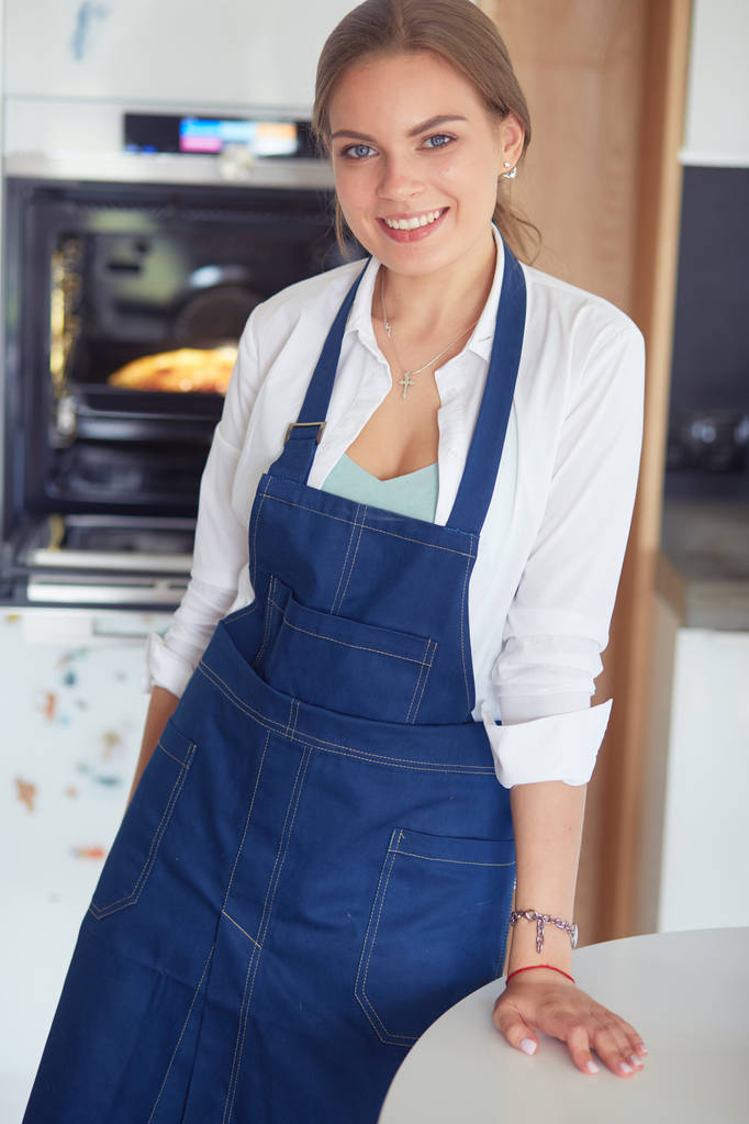 Retrato de mujer joven de pie con los brazos cruzados contra el fondo de la cocina - Foto, Imagen