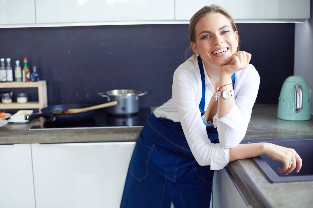 Portrét mladé ženy stojící s rukama zkříženýma na pozadí kuchyně - Fotografie, Obrázek