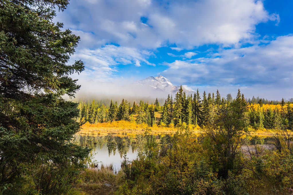Патрисия Лейк среди сосен. Гора пирамиды среди тумана и облаков. Скалистые горы в Канаде. Концепция экотуризма
 - Фото, изображение