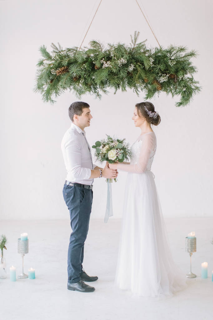 Mariée heureuse et marié après la cérémonie de mariageCérémonie de mariage dans une pièce blanche claire décorée de fleurs et de bougies
. - Photo, image