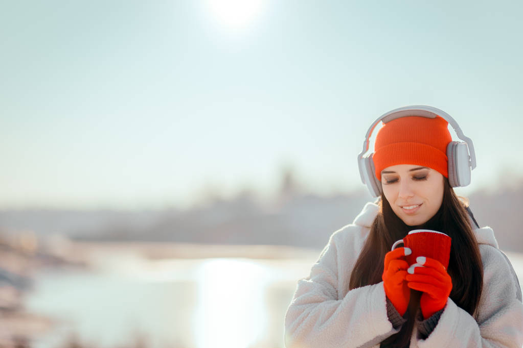 音楽を聴いてのホットド リンクを飲んで冬の女性 - 写真・画像
