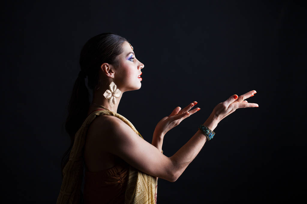 Kaukasische brunette vrouw in bruin Indiase nationale klederdracht sari in donkere studio achtergrond  - Foto, afbeelding