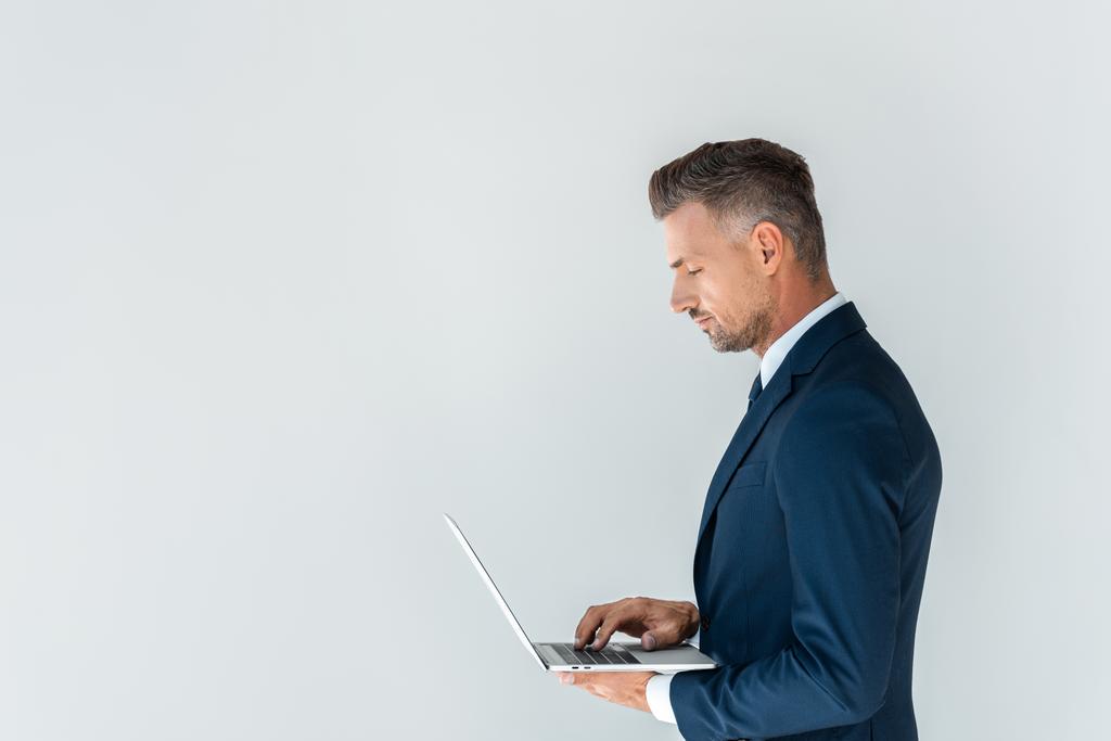 vista lateral del hombre de negocios guapo usando el ordenador portátil aislado en blanco
 - Foto, imagen