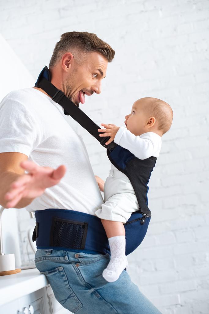 hauska isä näyttää kielen vauvalle kotona
  - Valokuva, kuva
