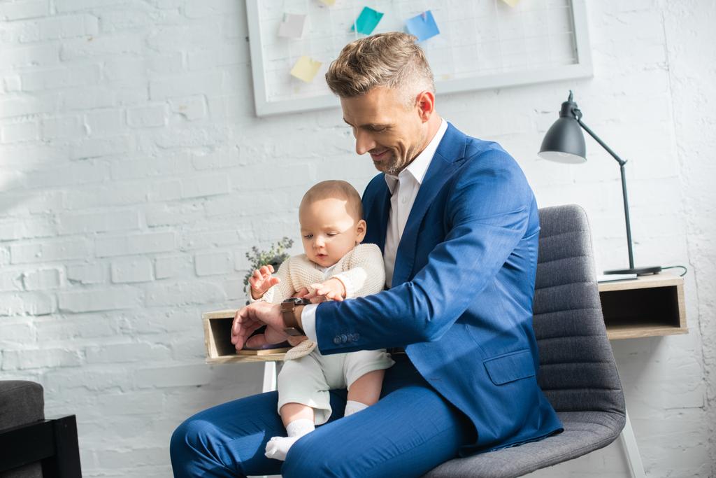 красивий бізнесмен, показуючи годинник дочці немовляти в кімнаті
  - Фото, зображення