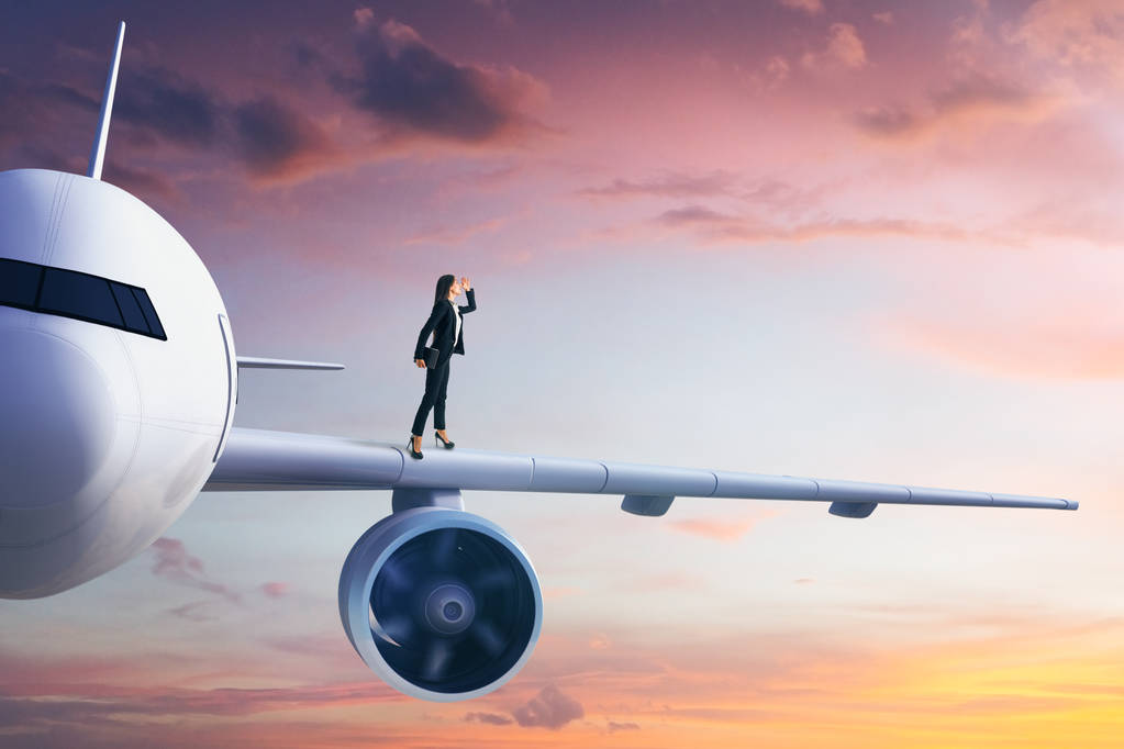 Seitenansicht einer jungen europäischen Geschäftsfrau, die in die Ferne blickt, während sie auf einem weißen Flugzeug am blauen Himmel steht. Transport- und Reisekonzept. - Foto, Bild