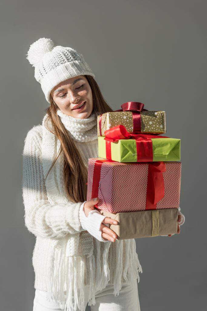 attraktive Frau in trendigem Winterpullover und Schal mit Geschenken vereinzelt auf grau - Foto, Bild