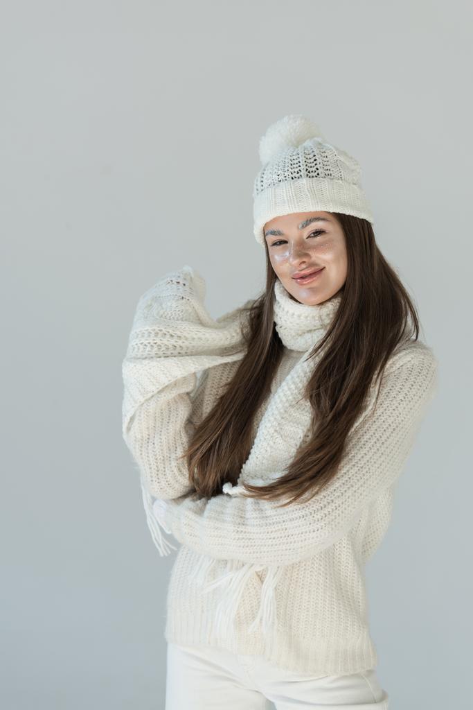 mulher atraente feliz em camisola de inverno na moda e cachecol olhando para a câmera isolada no branco
 - Foto, Imagem