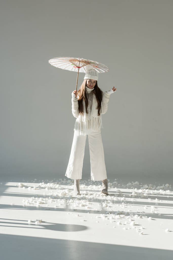おしゃれな冬のセーター、マフラーの白地の紙傘の側に立って魅力的な女性 - 写真・画像