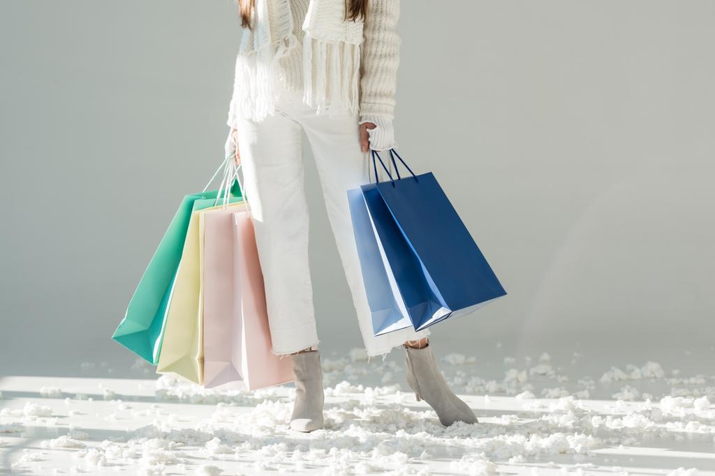 oříznutý obraz ženy v módní zimní svetr a šála s nákupní tašky na bílém - Fotografie, Obrázek