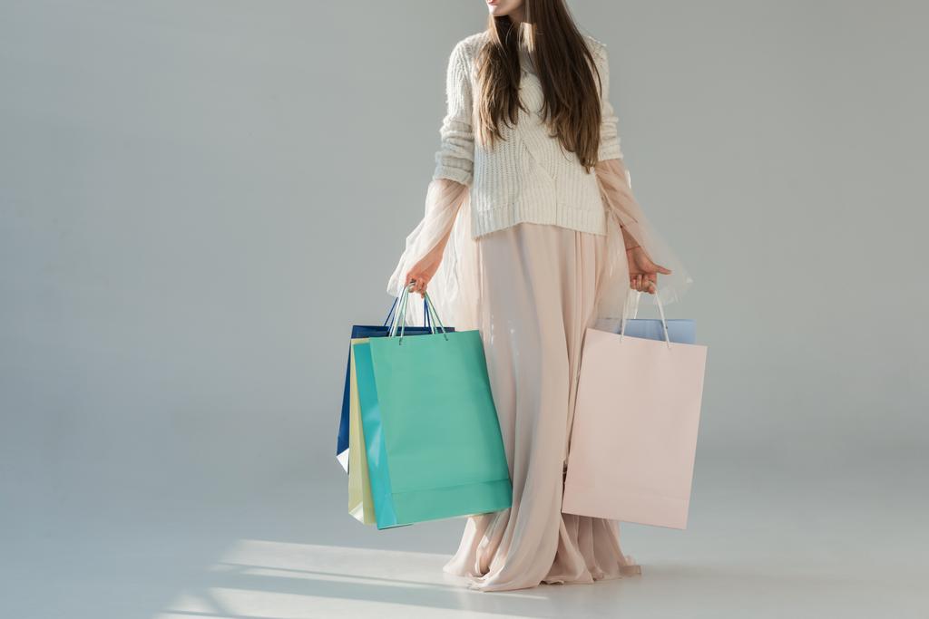 immagine ritagliata di donna in abito invernale alla moda in piedi con borse della spesa su bianco
 - Foto, immagini