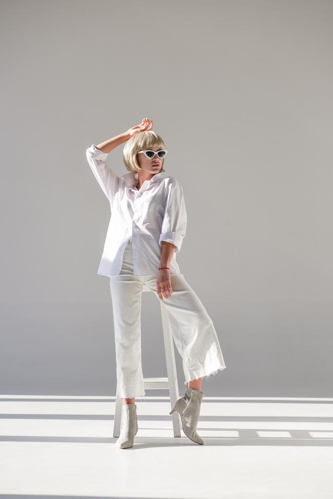 attractive blonde woman in sunglasses and fashionable white outfit posing on white - Photo, Image
