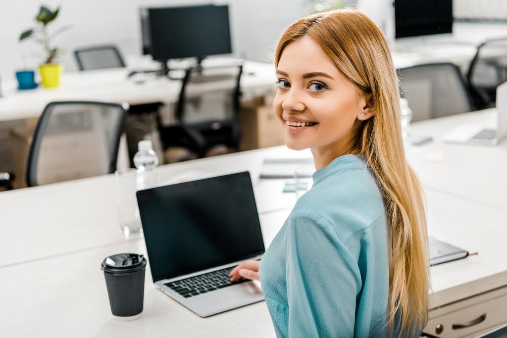 улыбающаяся деловая женщина на рабочем месте с ноутбуком и кофе, чтобы пойти в офис
 - Фото, изображение