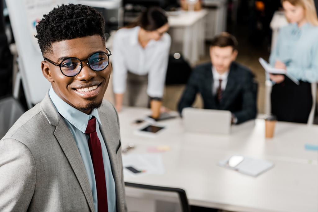 foco seletivo do sorridente empresário afro-americano e colegas de trabalho no escritório
 - Foto, Imagem