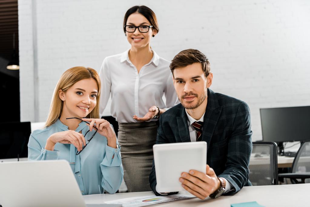 portrait d'homme d'affaires avec tablette et femmes d'affaires sur le lieu de travail avec ordinateur portable au bureau
 - Photo, image