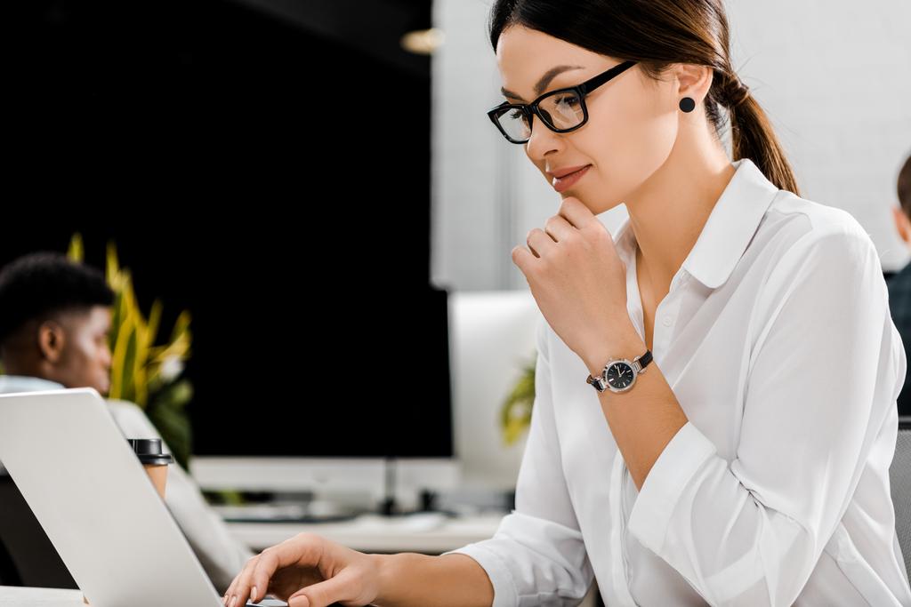 jovem empresária em óculos trabalhando no laptop no local de trabalho no escritório
 - Foto, Imagem