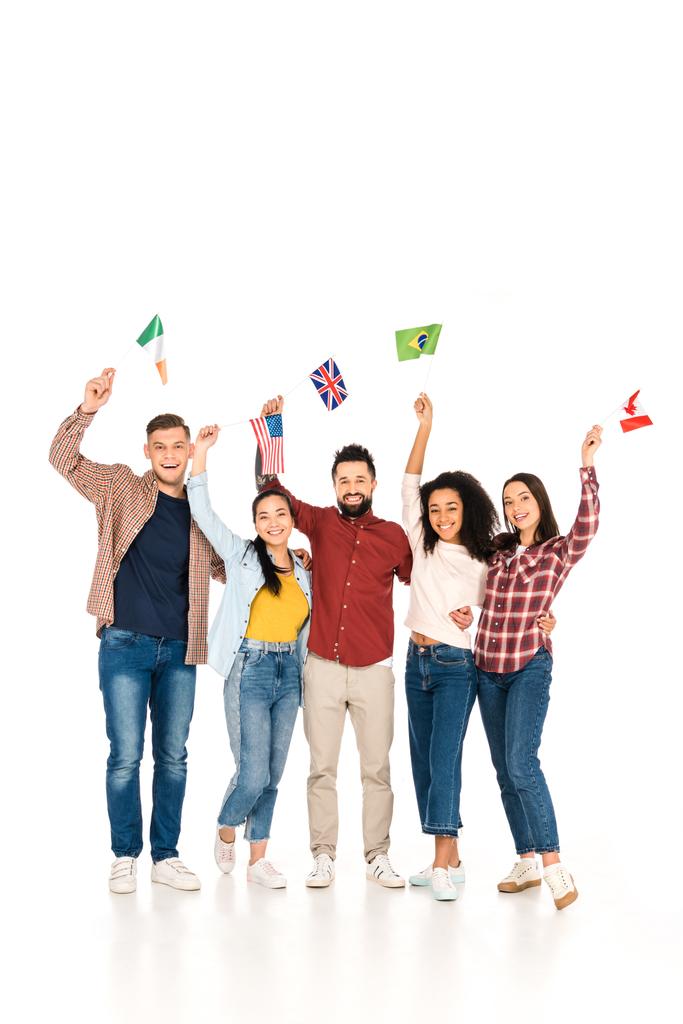 vrolijke multiculturele groep mensen glimlachen met vlaggen van verschillende landen boven hoofden geïsoleerd op wit - Foto, afbeelding