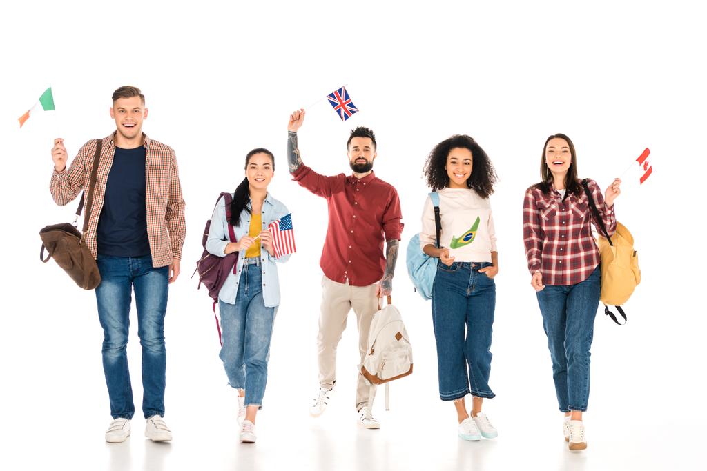 multiethnische Gruppe von Menschen mit Rucksäcken und Flaggen verschiedener Länder isoliert auf weiß  - Foto, Bild