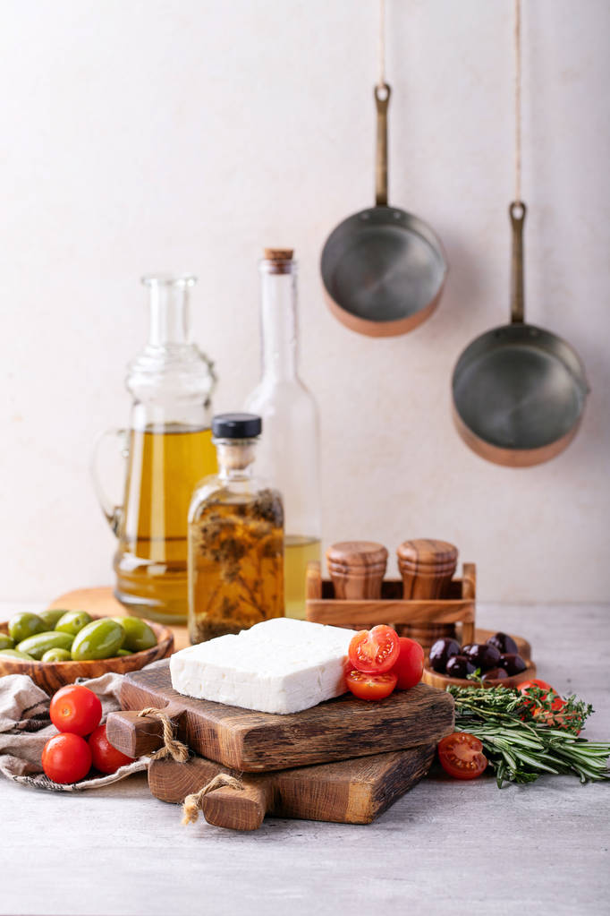 Apéritif grec traditionnel fromage feta de chèvre servi avec tomates cerises fraîches, herbes, olives vertes et noires et huile d'olive extra vierge sur fond gris
. - Photo, image