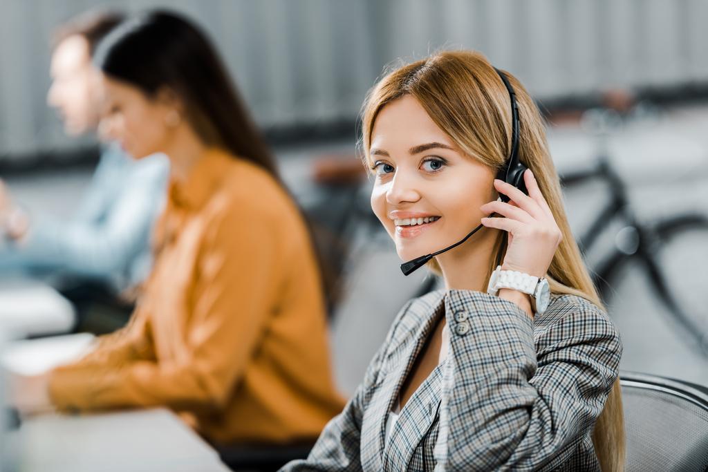 selective focus of smiling call center operator looking at camera in office - Photo, Image
