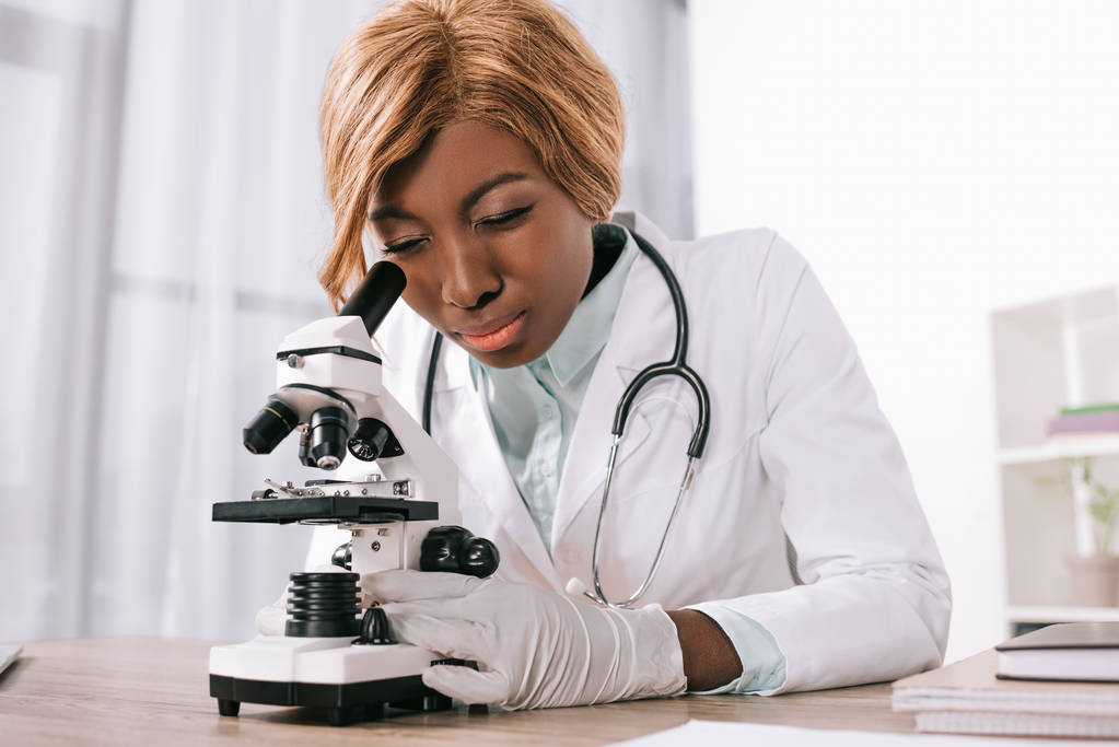 アフリカ系アメリカ人の科学者が顕微鏡を通して見る集中 - 写真・画像