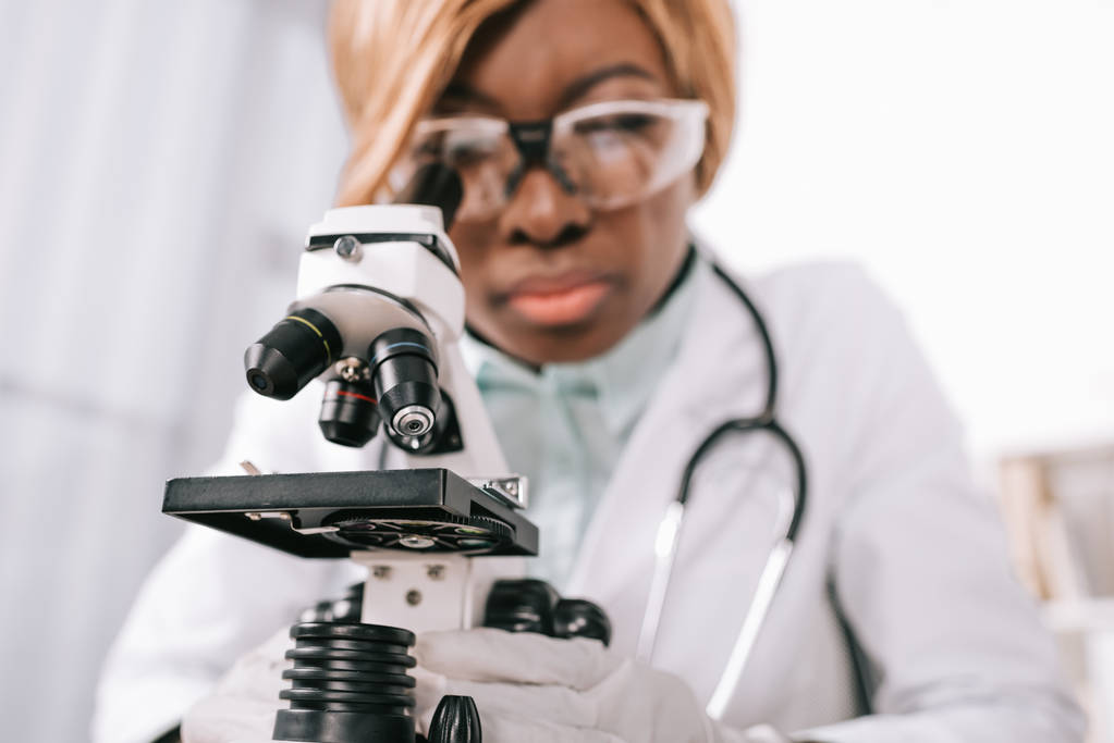 顕微鏡の背景に女性のアフリカ系アメリカ人科学者の選択と集中 - 写真・画像