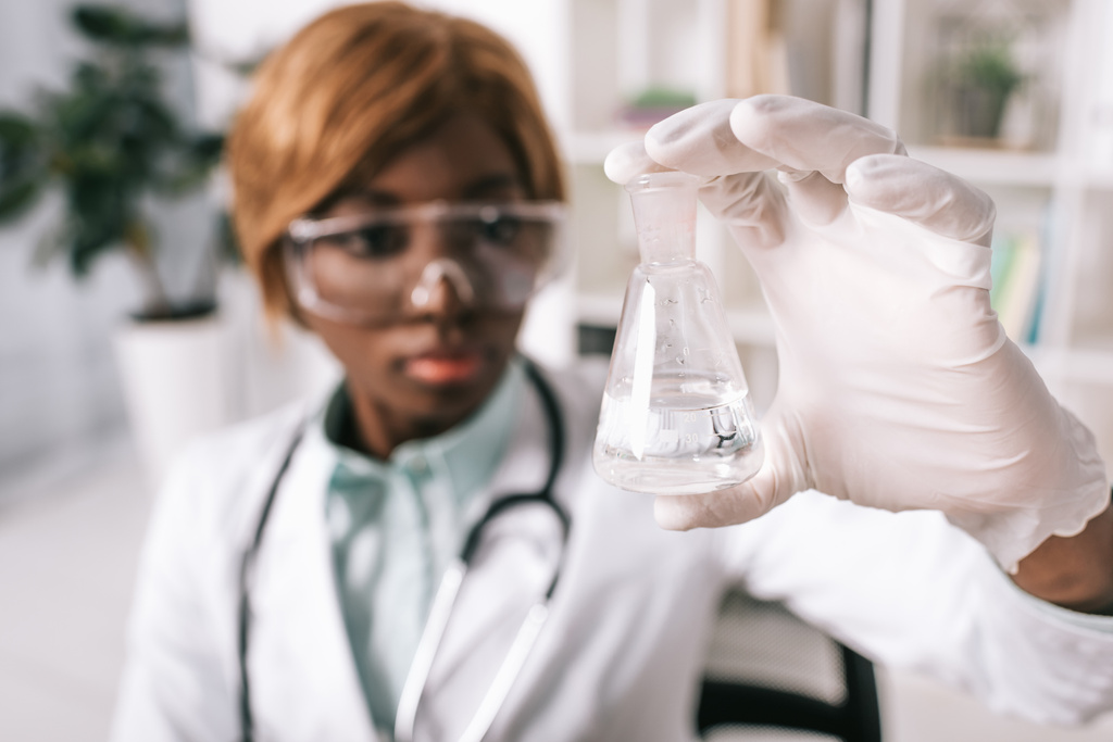 вибірковий фокус скляної пробірки з рідиною в руці афроамериканського американського вченого
  - Фото, зображення